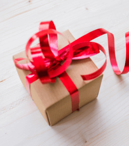 Cadeau emballé dans du papier kraft avec un ruban rouge – marchés de Noël Symbiose Herboristerie
