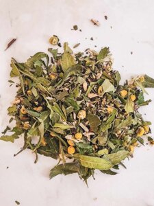 Mélange de plantes séchées pour tisane : feuilles et fleurs en vrac sur fond blanc